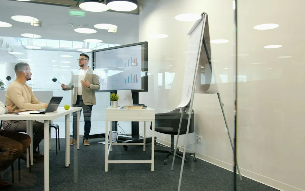 A presenter discussing charts with colleagues in a meeting room.