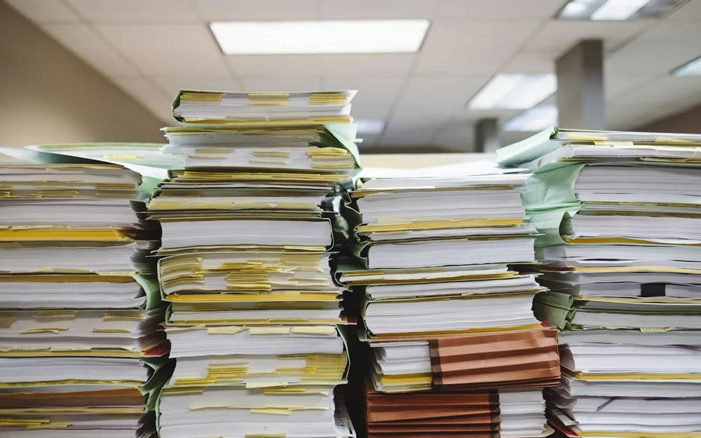 Stacks of paper records held in tabbed file folders.