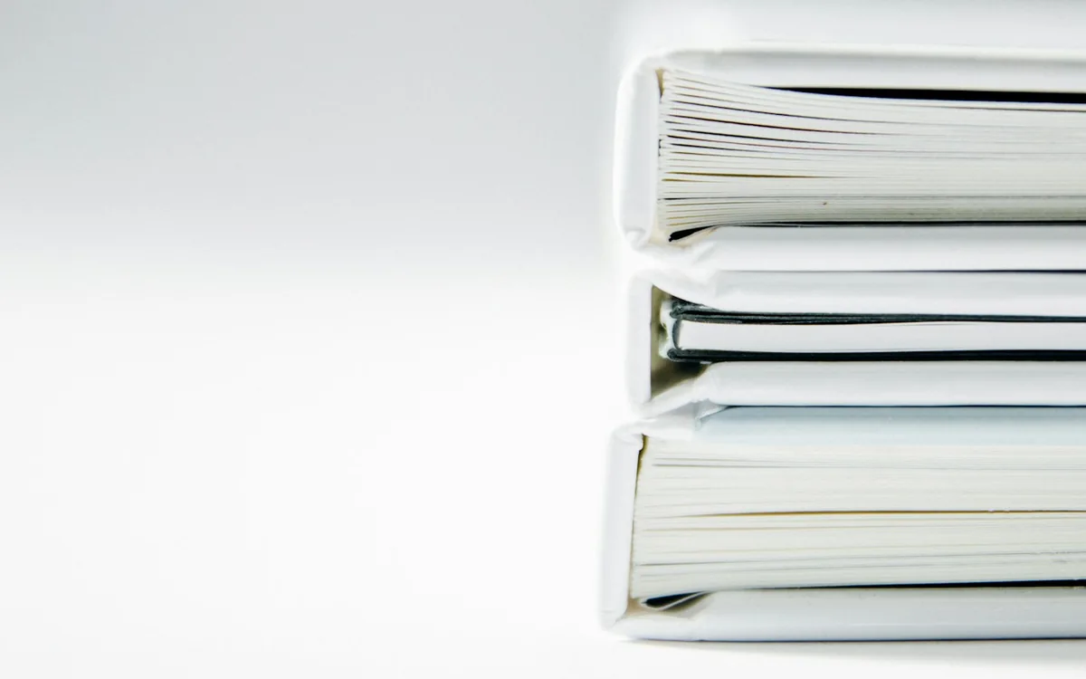 Three thick folders of paper records stacked on a pale surface.